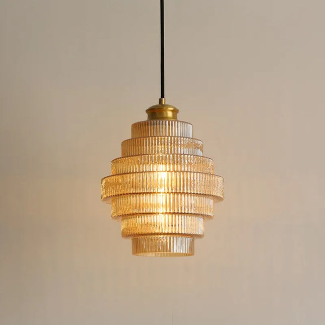 Suspension nordique en verre strié étagé à paliers, finition dorée et culot brass, sur fond beige