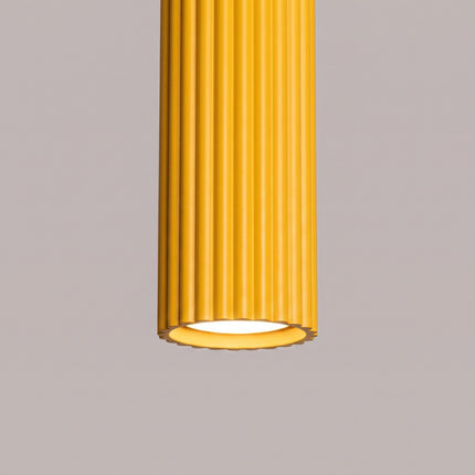 Suspension Oslo 1 Cylindre en Aluminium Cannelé Jaune Ambré, vue sur fond coloré