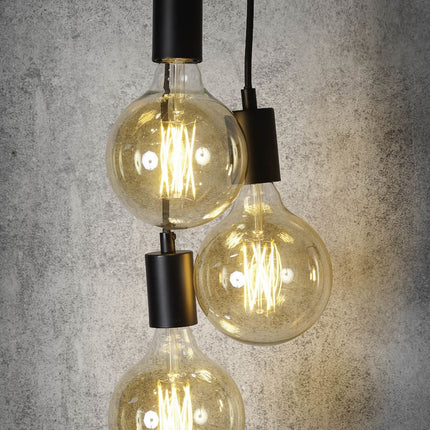 Trois ampoules globe allumées suspendues aux douilles noires de la suspension Oslo