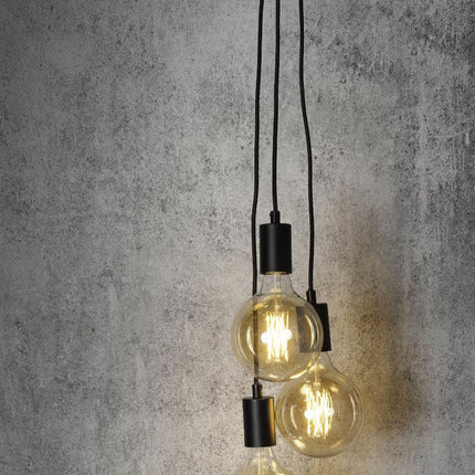 Gros plan sur les trois douilles noires et câbles textiles de la suspension Oslo, ampoules allumées