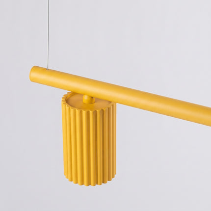 Suspension Oslo poutre 4 cylindres 122 cm jaune ambré sur fond coloré, vue de trois quarts