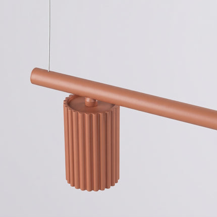 Suspension Oslo Poutre 4 Cylindres 122 cm en Aluminium Cannelé Rouge Ocre, vue sur fond coloré