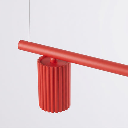 Suspension Oslo poutre 4 cylindres 122 cm rouge vif sur fond coloré, vue de trois quarts