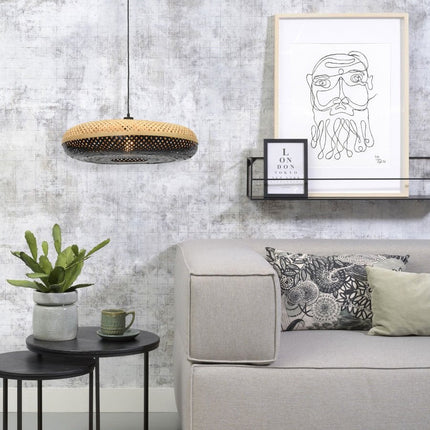 Pendant light Palawan in black braided bamboo and natural above a beige sofa and of a plant
