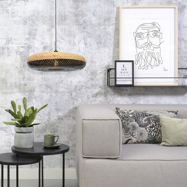 Pendant light Palawan in black braided bamboo and natural above a beige sofa and of a plant