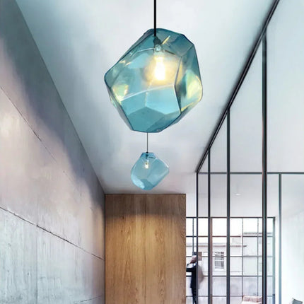 Deux suspensions pierre en verre bleu étagées dans un couloir contemporain en béton