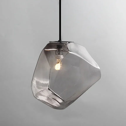 Suspension pierre en verre gris fumé allumée, forme de galet facetté, sur fond neutre