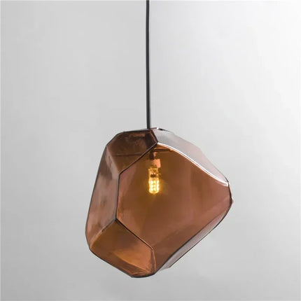 Suspension pierre en verre marron cognac allumée, forme de galet facetté, sur fond neutre