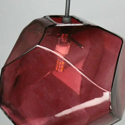 Gros plan sur une suspension pierre en verre rouge et son ampoule G4 apparente