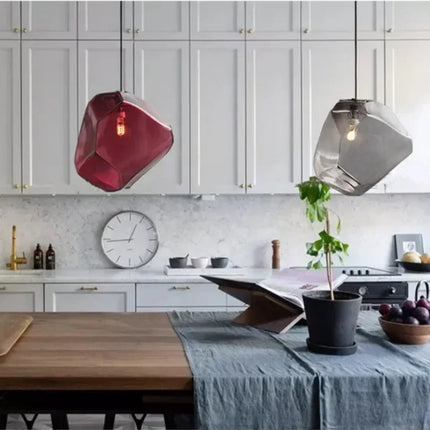 Suspensions pierre en verre rouge et gris fumé au-dessus d'une table dans une cuisine claire