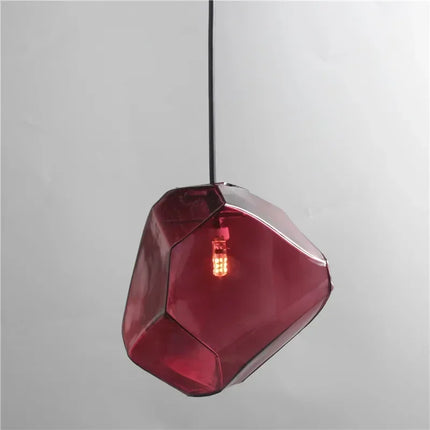 Suspension pierre en verre rouge grenat allumée, forme de galet facetté, sur fond neutre