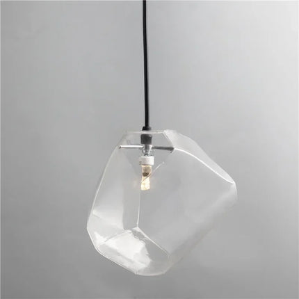 Suspension pierre en verre transparent allumée, forme de galet facetté, sur fond neutre