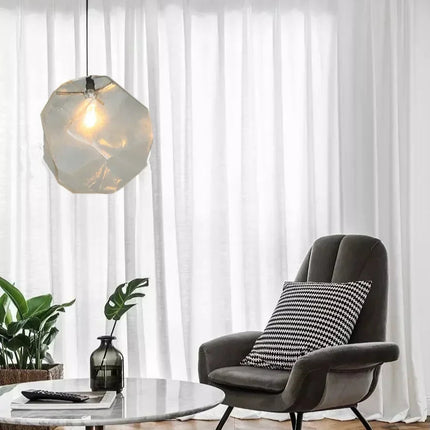 Suspension pierre en verre transparent près d'un fauteuil gris dans un salon voilé
