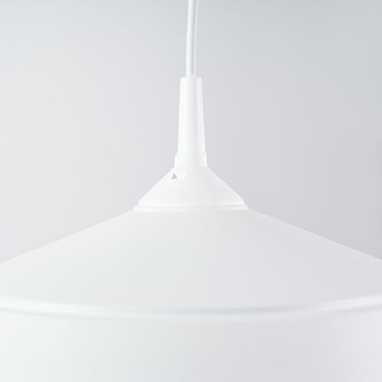 Gros plan sur la suspension Pur Frika blanc mat allumee pres d'un mur strie