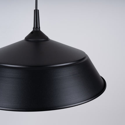 Suspension Pur Frika noir mat eclairant une chambre avec plantes vertes et coussins colores