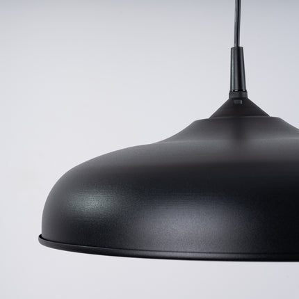 Suspension Pur Gina noir mat en mise en situation, lumiere chaude diffusee sur le mur