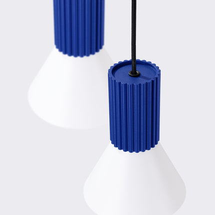 suspension ronde 3 cônes blancs à fût cannelé bleu outremer, vue sur fond coloré
