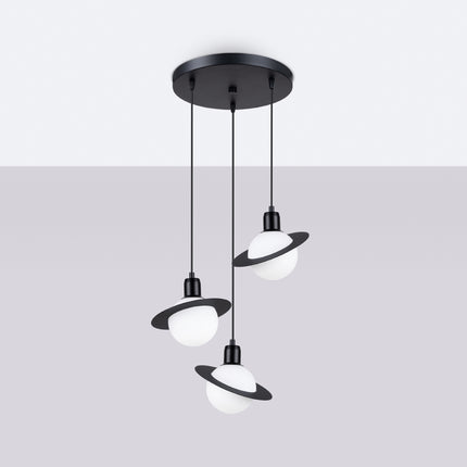 Suspension Saturne 3 lumières noire allumée, la lumière chaude traverse les globes opalins pour une ambiance douce.