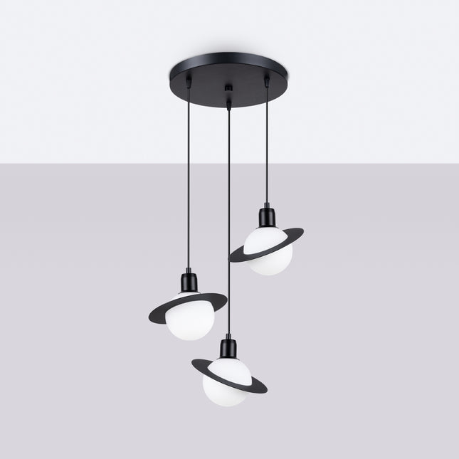Suspension Saturne 3 lumières noire allumée, la lumière chaude traverse les globes opalins pour une ambiance douce.