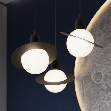 Suspension Saturne noire installée près d'un lit, vue rapprochée illustrant son rendu doux en chevet.