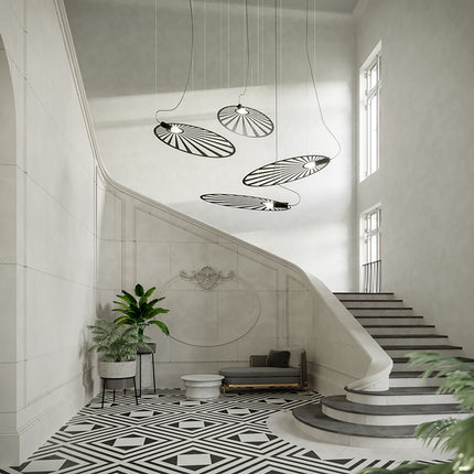 Quatre suspensions Soleil Lumineux noires groupées dans une cage d'escalier design