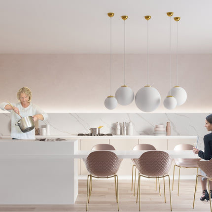 Suspensions sphères opalines dorées au-dessus d'une table de repas dans une cuisine lumineuse