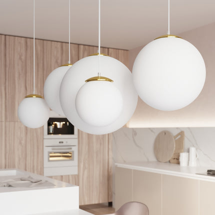 Alignement de suspensions globes opalins dorés de différents diamètres dans une cuisine contemporaine