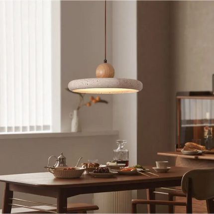 Suspension plate en travertin et sphère de bois clair suspendue au-dessus d'une table de salle à manger