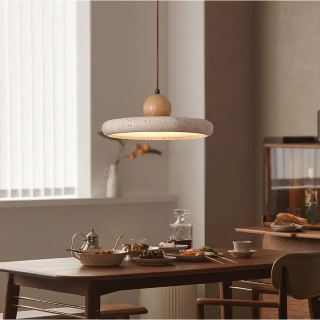 Suspension plate en travertin et sphère de bois clair suspendue au-dessus d'une table de salle à manger