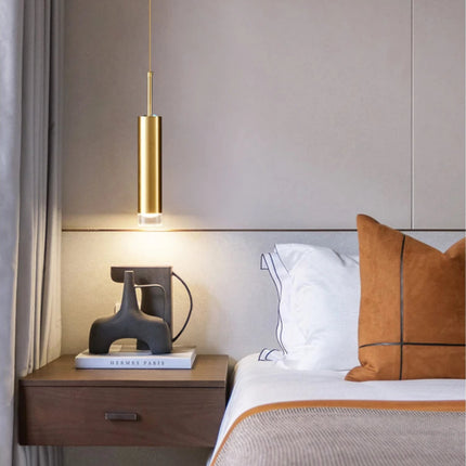 Suspension tube doré à 1 tête éclairant une table de chevet en bois dans une chambre élégante