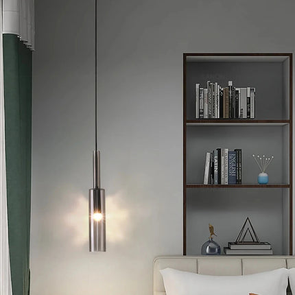 Suspension tube verre fumé et métal noir dans une chambre avec bibliothèque et rideau vert