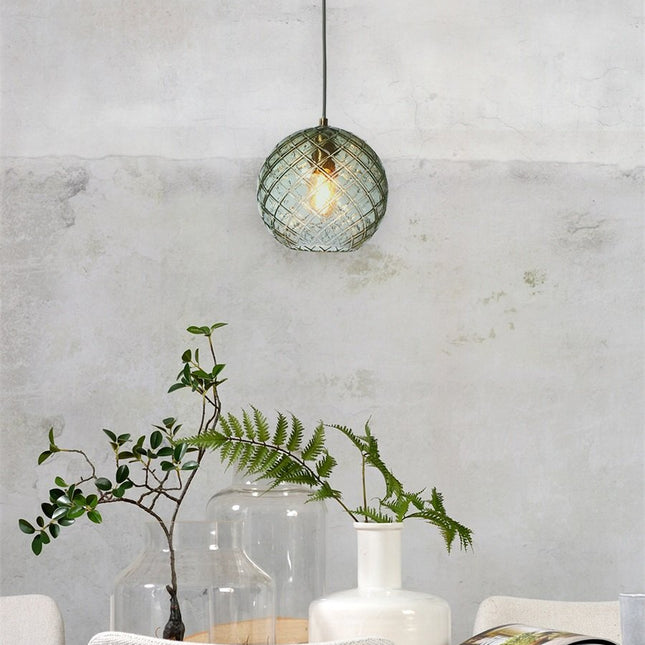Suspension Venice globe en verre soufflé vert quadrillé suspendue devant un mur en béton brut