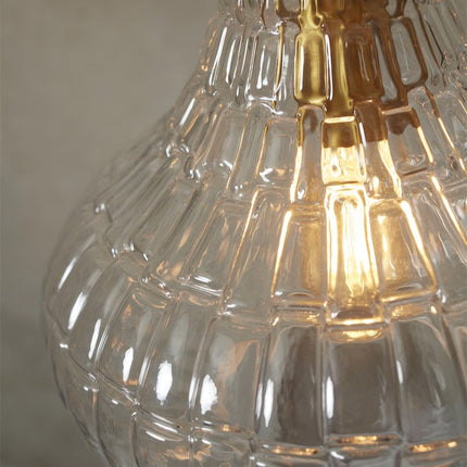 Gros plan sur la texture gaufrée du verre transparent et la finition dorée de la suspension Venice