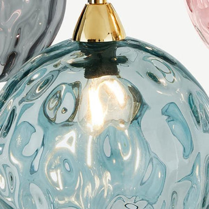 Détail d'un globe en verre soufflé martelé bleu montrant les reliefs texturés et l'embout doré