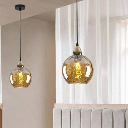 Deux suspensions à globe en verre martelé ambré clair suspendues près d'un voilage