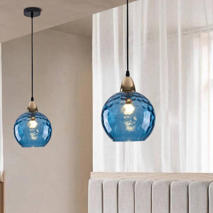 Deux suspensions à globe en verre martelé bleu suspendues au-dessus d'une tête de lit