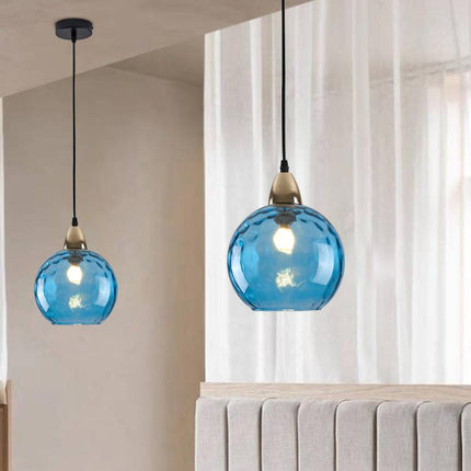 Deux suspensions à globe en verre martelé bleu vif au-dessus d'une tête de lit capitonnée