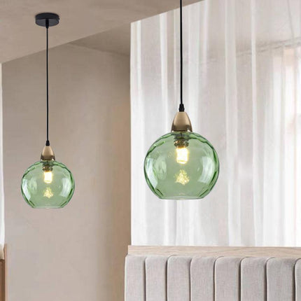 Deux suspensions à globe en verre martelé vert installées à hauteurs décalées dans une chambre