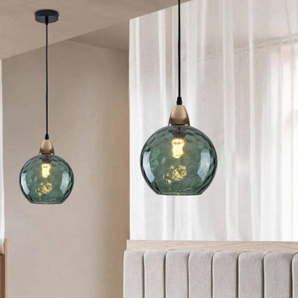 Deux suspensions à globe en verre martelé vert foncé suspendues au-dessus d'une tête de lit