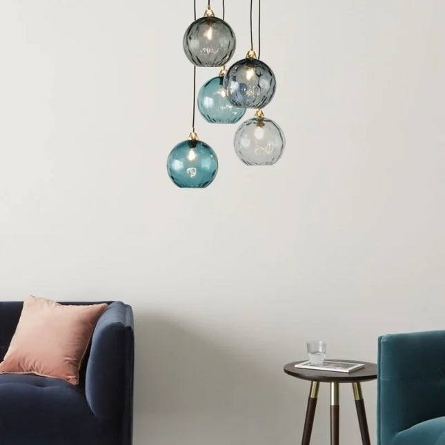 Grappe de cinq suspensions en verre martelé aux tons bleus et gris au-dessus d'un salon