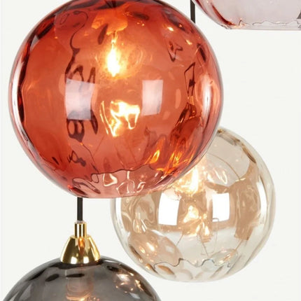 Gros plan sur des globes en verre martelé coloré et leurs embouts coniques dorés