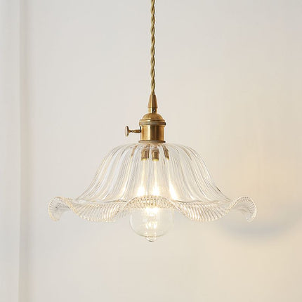 Suspension en verre ondulé floral transparent allumée devant un mur blanc dans un intérieur épuré