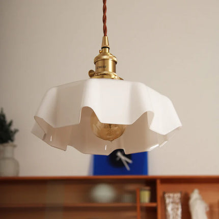 Suspension en verre opalin blanc allumée, ampoule visible sous l'abat-jour plissé, lumière chaude
