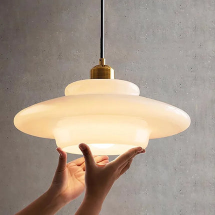 Détail de l'abat-jour soucoupe en verre opalin crème tenu à la main