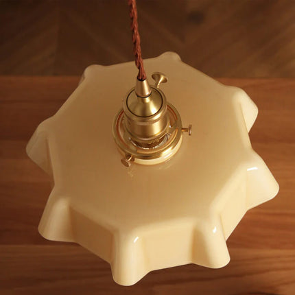 Vue de dessous de la suspension en verre crème à la forme ondulée en étoile et douille en laiton
