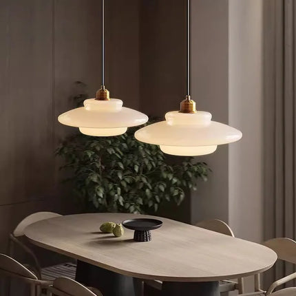 Deux suspensions soucoupe en verre opalin crème au-dessus d'une table en bois