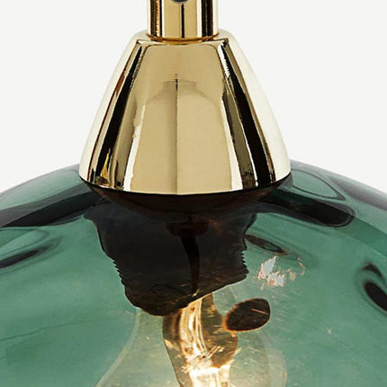 Gros plan sur l'embout conique doré posé sur un globe en verre soufflé vert translucide