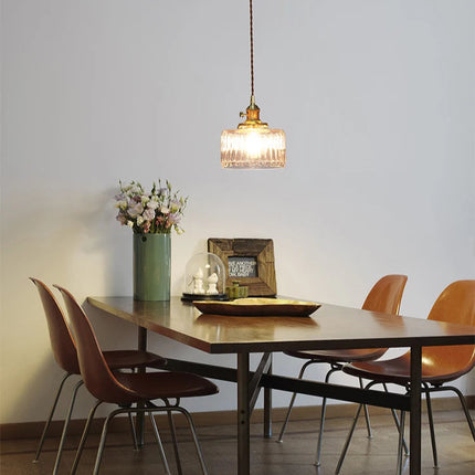 Suspension en verre strié allumée au-dessus d'une table de salle à manger en bois