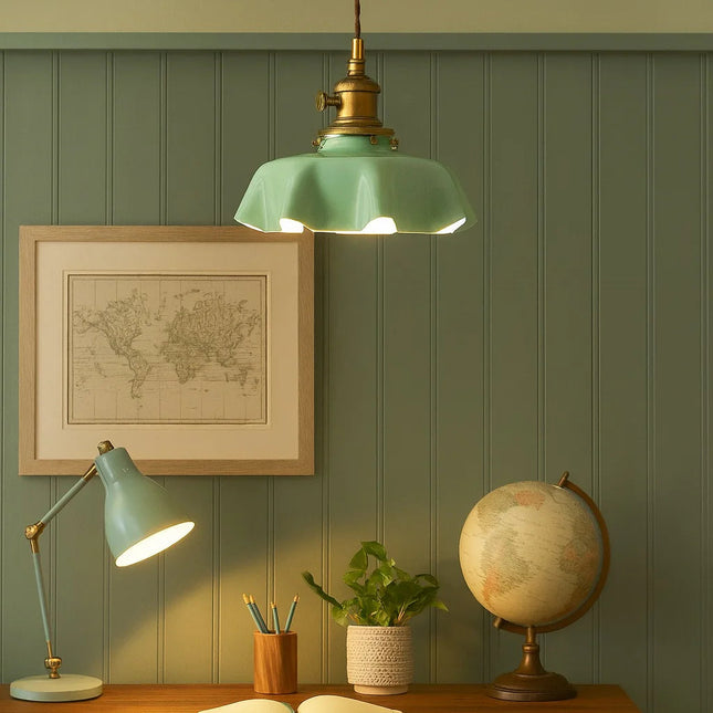 Suspension en verre vert allumée au-dessus d'un coin bureau aux murs verts et lampe assortie
