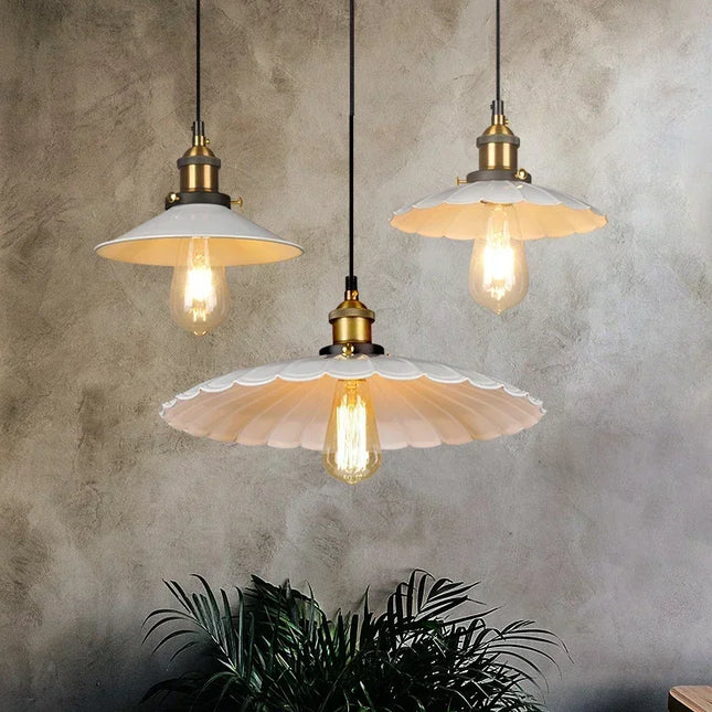 Trio de suspensions vintage festonnées en métal blanc au-dessus d'un mur béton avec plante verte